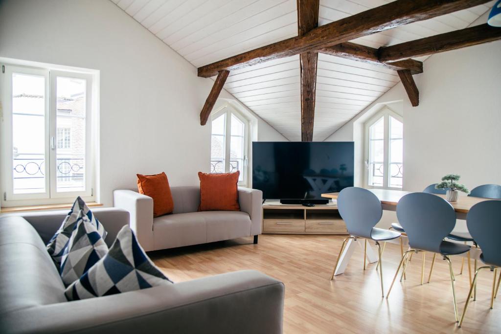 uma sala de estar com um sofá e cadeiras e uma televisão em Nimbuzzz Apartments em Unterseen