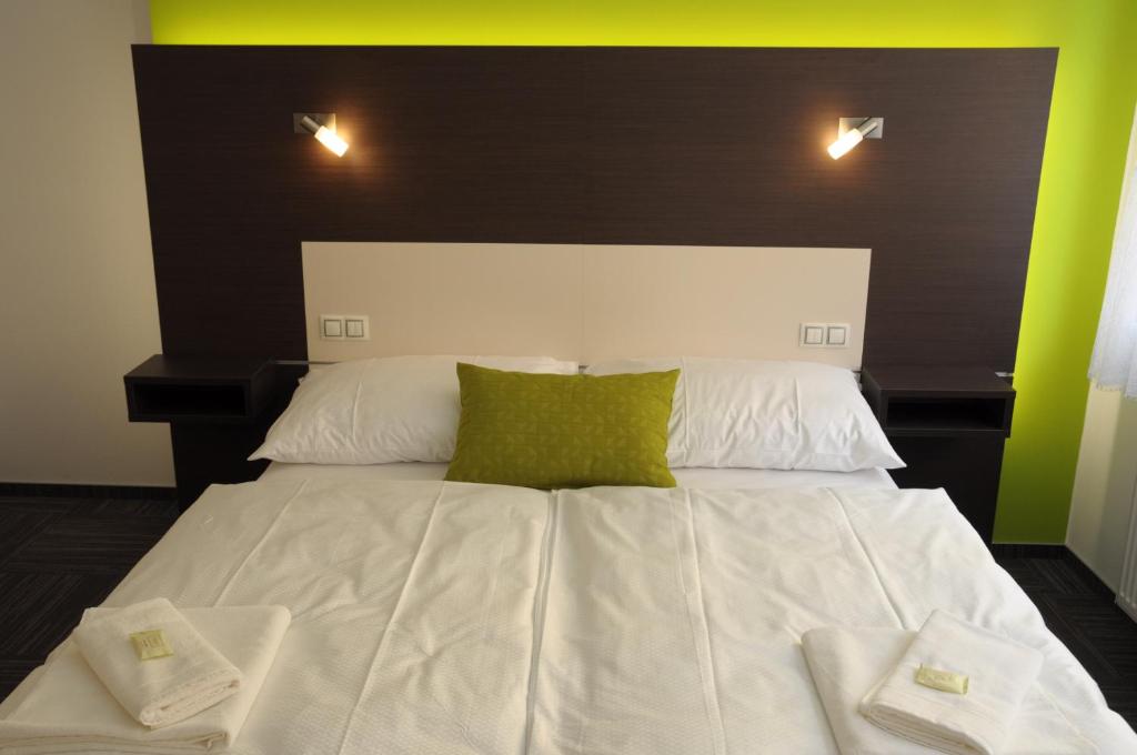 duże białe łóżko z 2 zielonymi poduszkami w obiekcie Hotel Kaskada w mieście Ledeč nad Sázavou