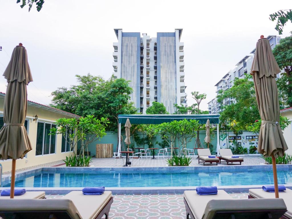Le Kree Downtown Hotel في بنوم بنه: مسبح بالطاولات والمظلات ومبنى