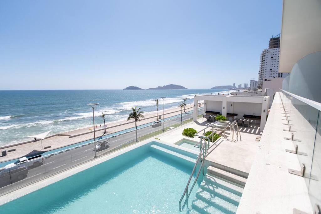 une piscine avec l'océan en arrière-plan dans l'établissement Cristal bay 503 Hermoso depa con vista al mar, à Mazatlán