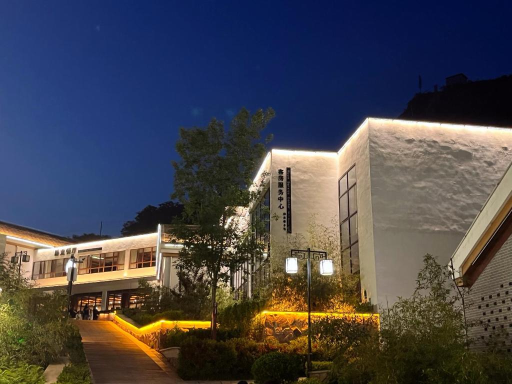 a building with lights on the side of it at night at Shijiazhuang Pingshan Golden Honzai Hotel in Pingshan