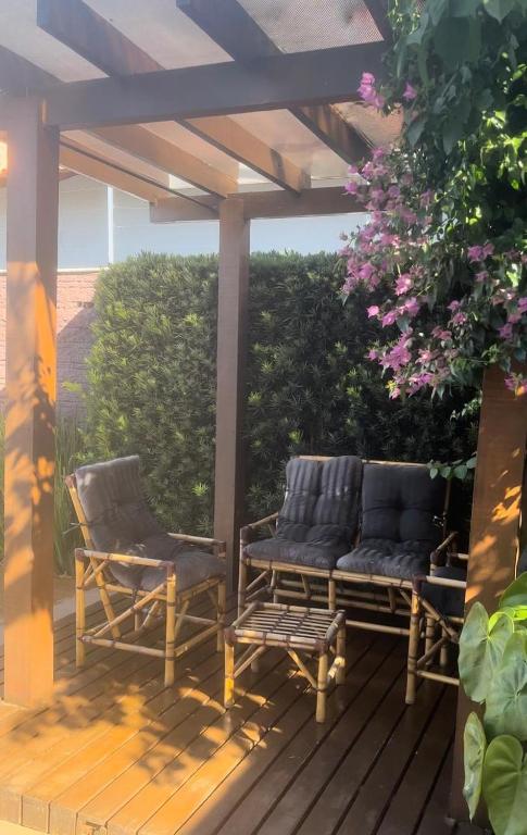 two chairs and a bench on a wooden deck at Casa com piscina in Cianorte