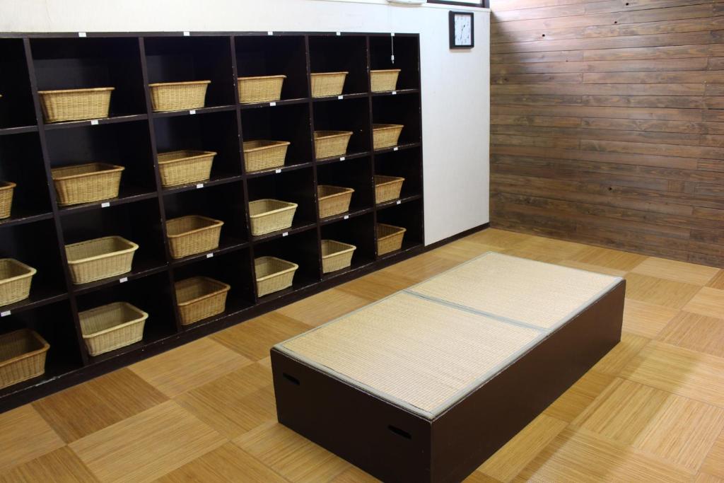 a room with a bed and shelves with baskets at Miyajima Seaside Hotel in Miyajima