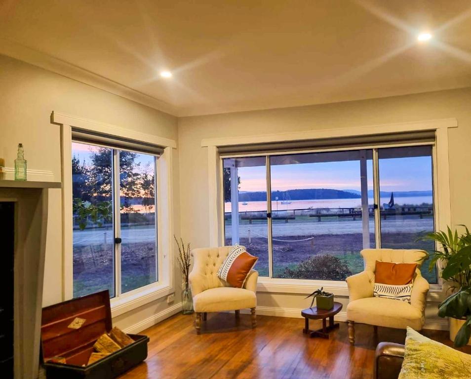 a living room with two chairs and large windows at Castaway Cottage in Dover