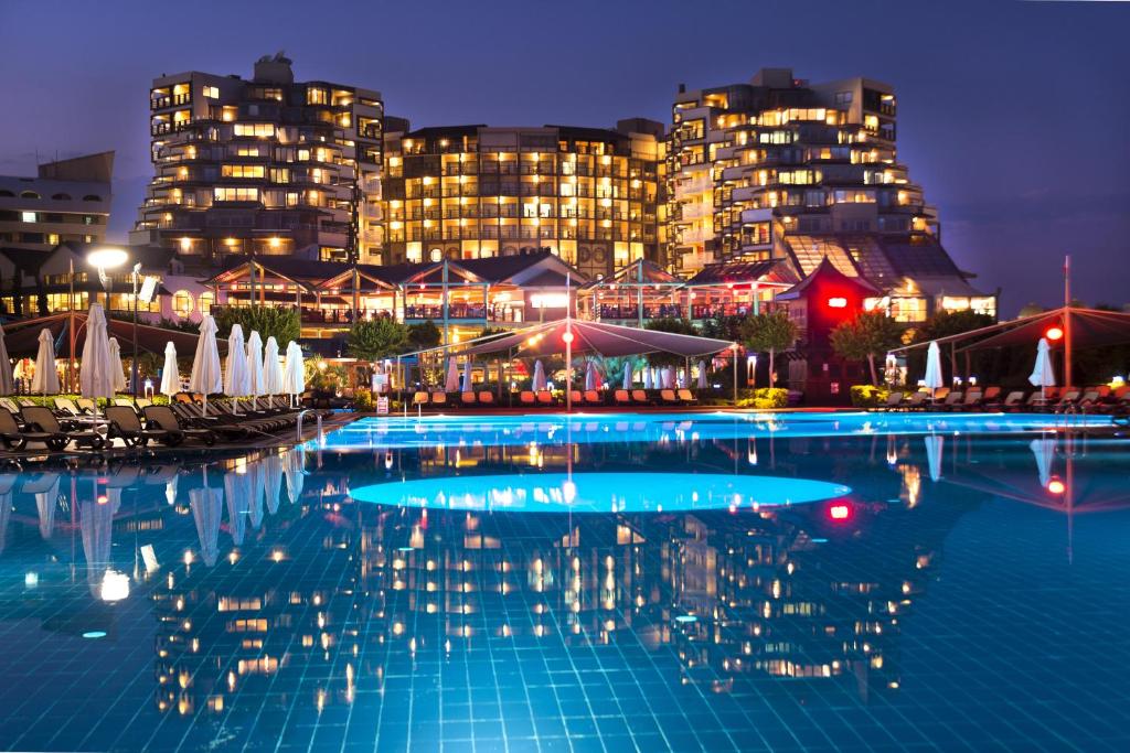 uma grande piscina com edifícios ao fundo em Limak Lara Deluxe Hotel & Resort Antalya em Lara