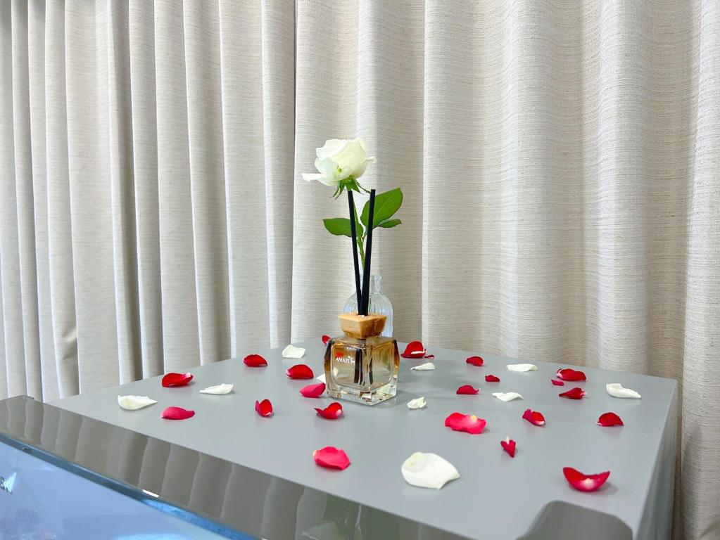um vaso com uma flor sobre uma mesa com pétalas de rosa vermelhas em Santa's House em Xiaoliuqiu