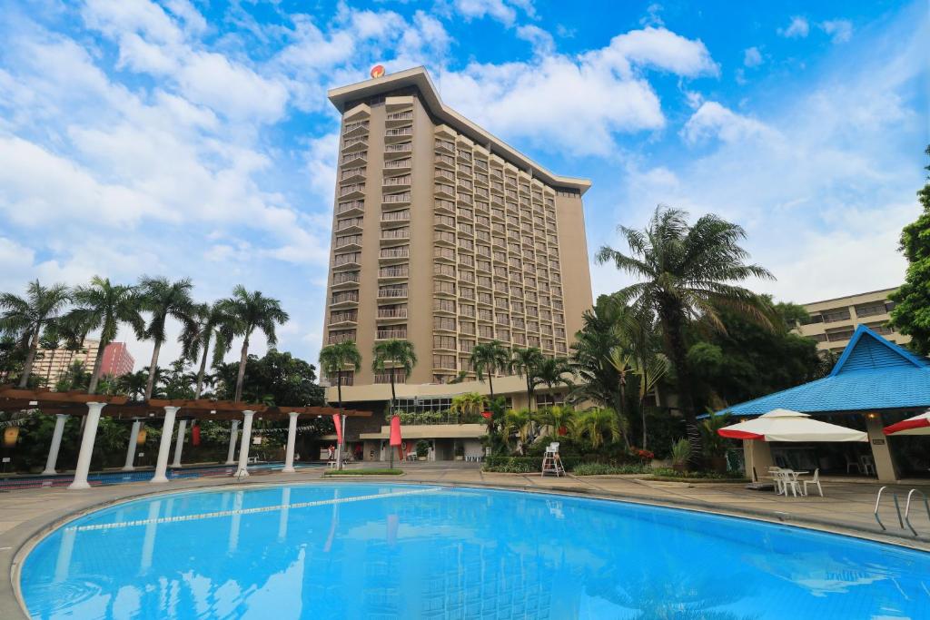 a large hotel with a large pool in front of it at Century Park Hotel in Manila