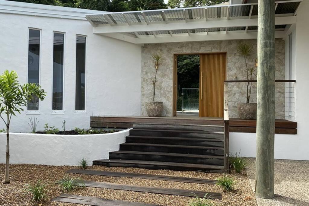 a white house with a wooden door and stairs at Casa Tropico - Mission Beach in Mission Beach