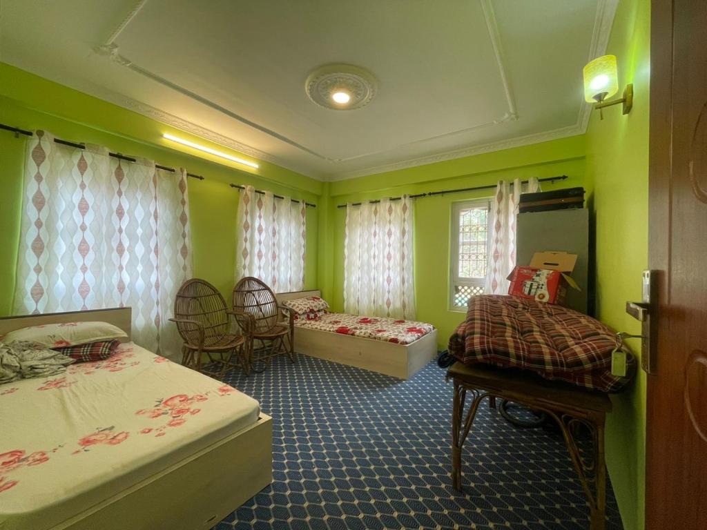 Cette chambre verte comprend 2 lits et des chaises. dans l'établissement Chovar homestay, à Kirtipur