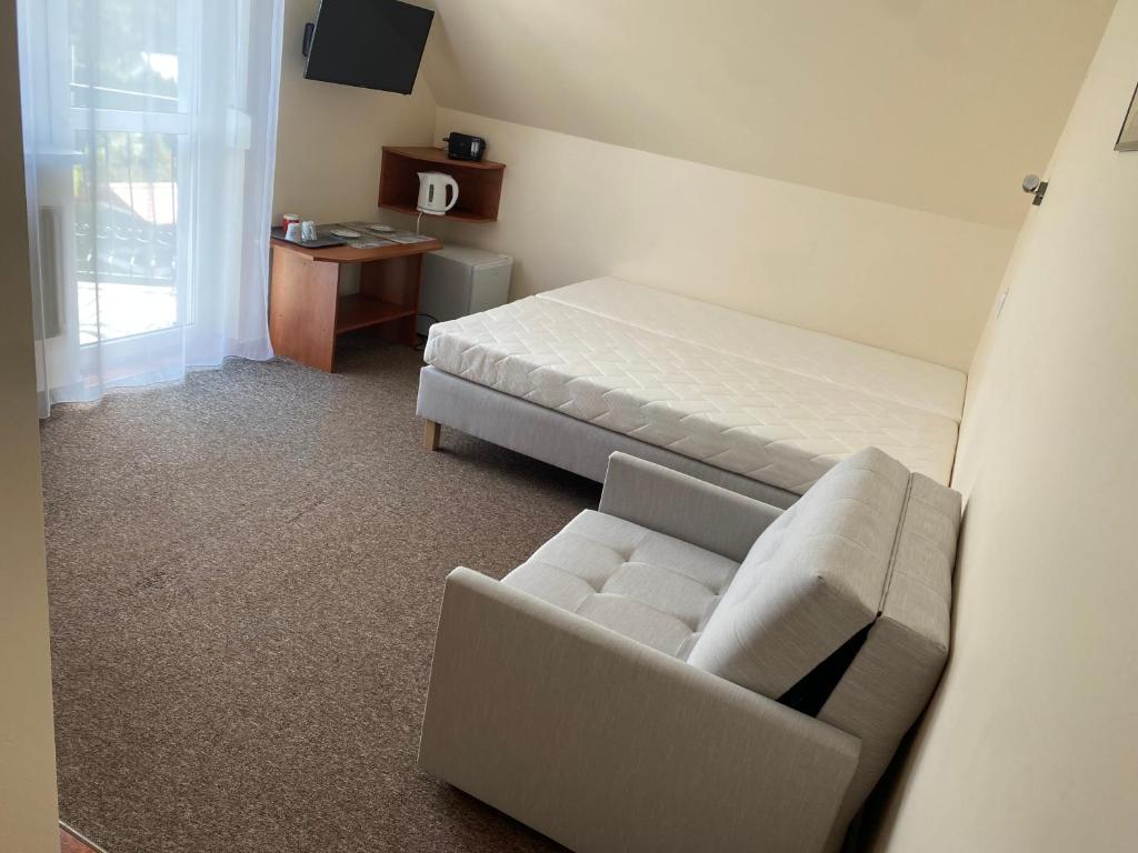 Zimmer mit einem Bett, einem Sofa und einem Stuhl in der Unterkunft DELFIN Pokoje Gościnne in Gąski