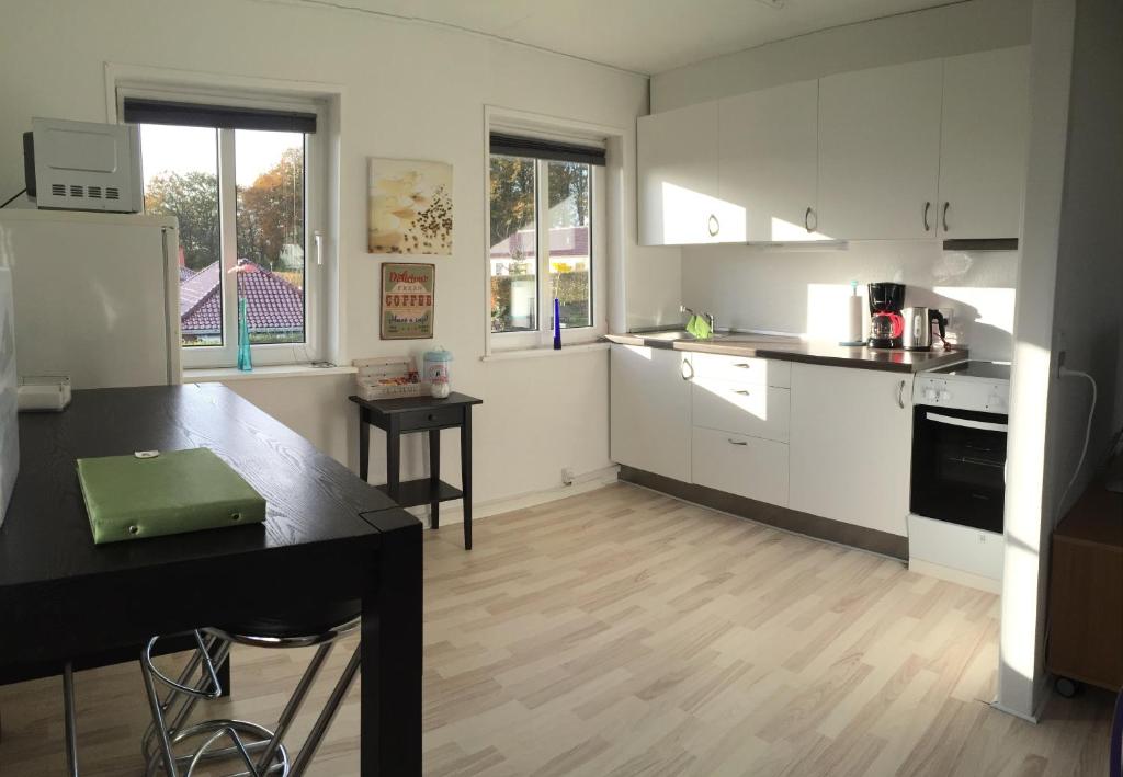 una cocina con armarios blancos y una mesa negra en una habitación en Vejle Apartment Skovhøjen, en Vejle