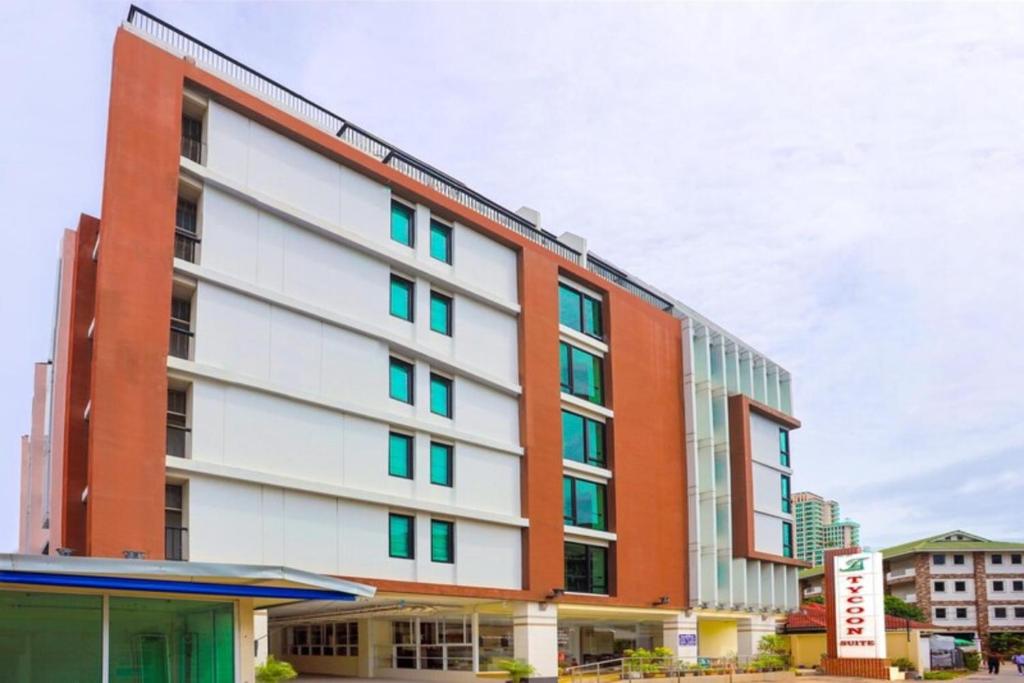 Un edificio naranja y blanco con ventanas verdes. en Tycoon suite pattaya, en Pattaya central