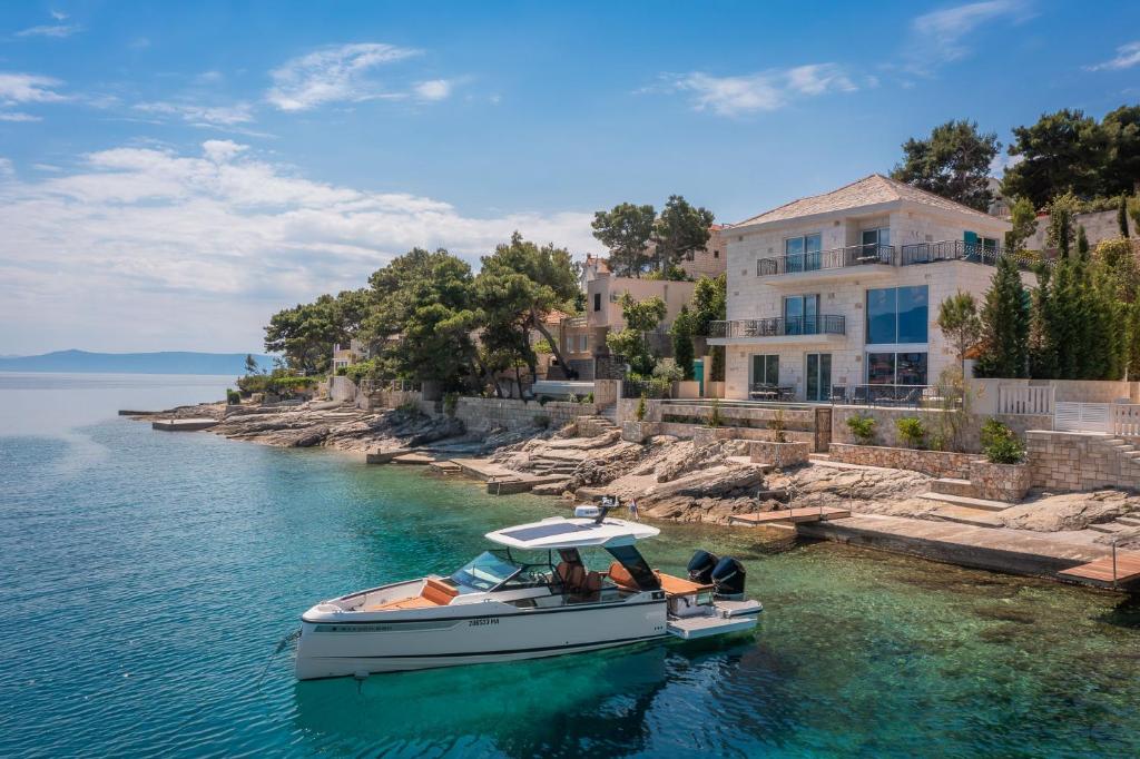 a boat in the water in front of a house at Villa Stara in Selca