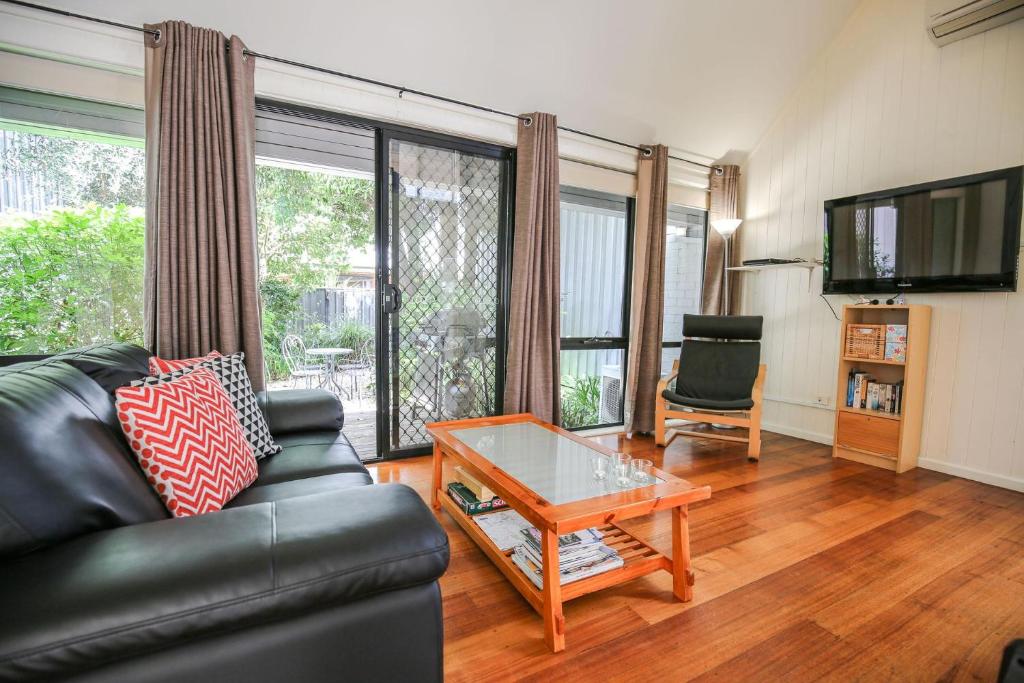 Allambie Cottages - Villa 2 في برايت: غرفة معيشة مع أريكة جلدية وطاولة