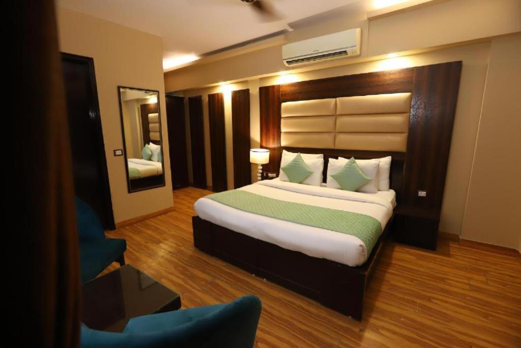 Airport Hotel Peebles في نيودلهي: غرفة نوم بسرير كبير ومرآة