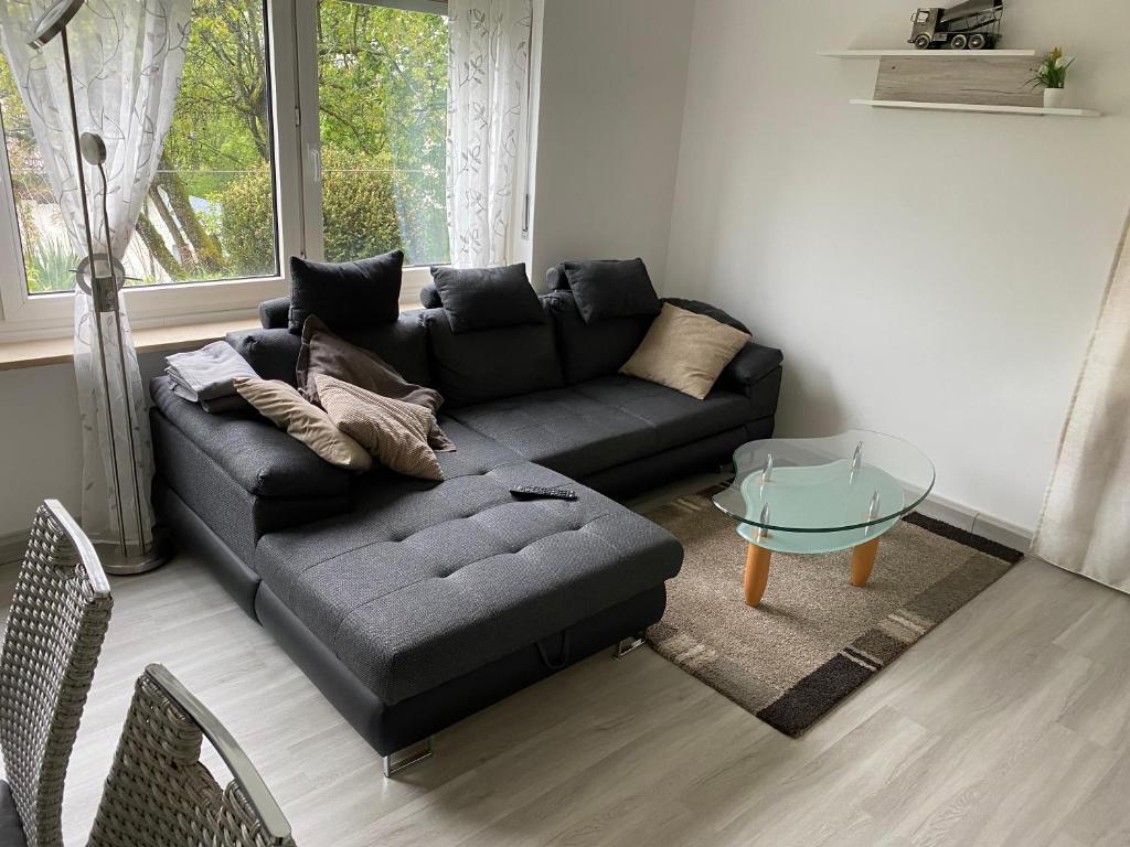 a living room with a black couch and a glass table at Erdgeschoss Wohnung 2 Schlafzimmer in Bayreuth