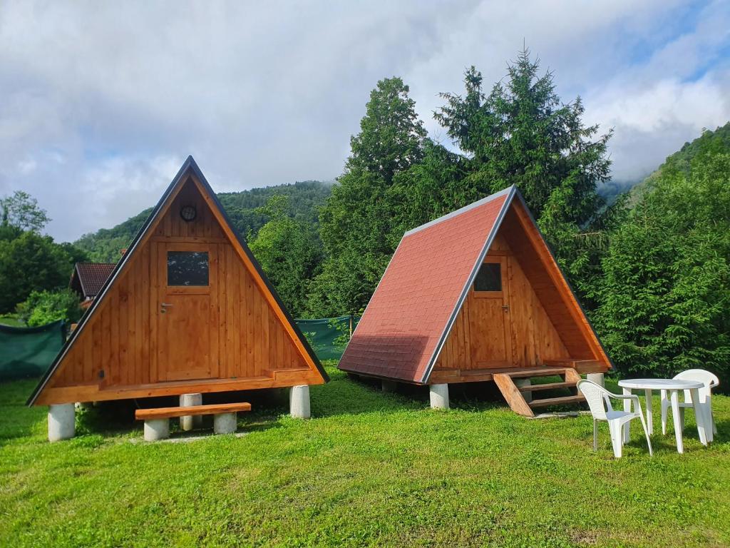 two houses on a field with a table and chairs at GLAMPING HOUSE ˇVITAˇ in Tolmin