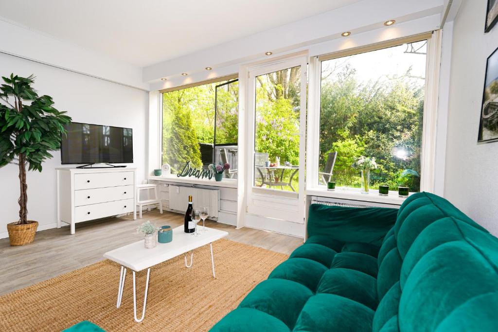 ein Wohnzimmer mit einem grünen Sofa und einem TV in der Unterkunft FeWo C 1-2 "Kleine Auszeit" in Sierksdorf