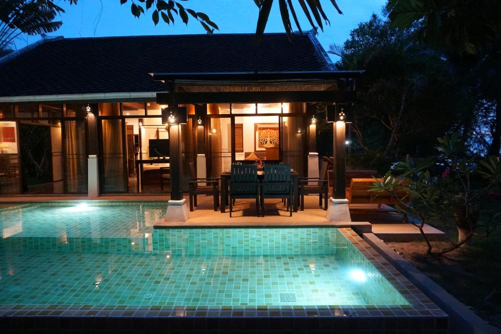 - une piscine en face d'une maison la nuit dans l'établissement Villa Emerald Sand - Beach Front 4 Bed Pool Villa, à Koh Samui 