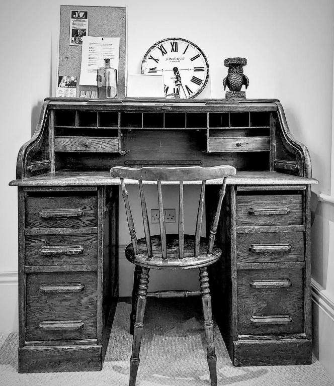 a desk with a chair and a clock on it at Church Retreat - A Magnificent Seaside Apartment-Award Winning in Hastings