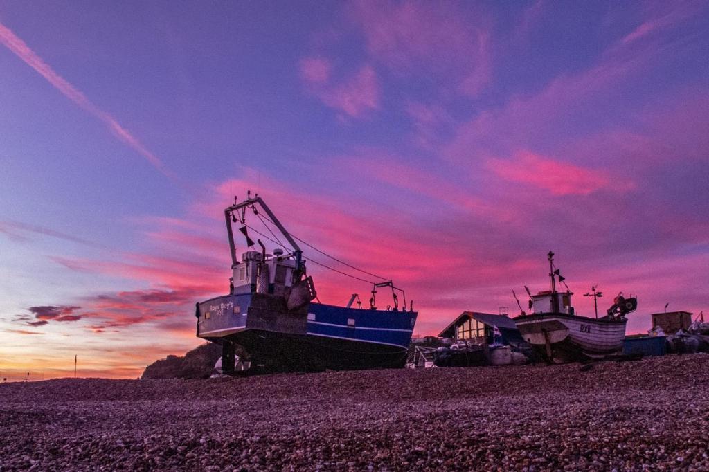 two boats sitting on the beach at sunset at Church Retreat - A Magnificent Seaside Apartment-Award Winning in Hastings