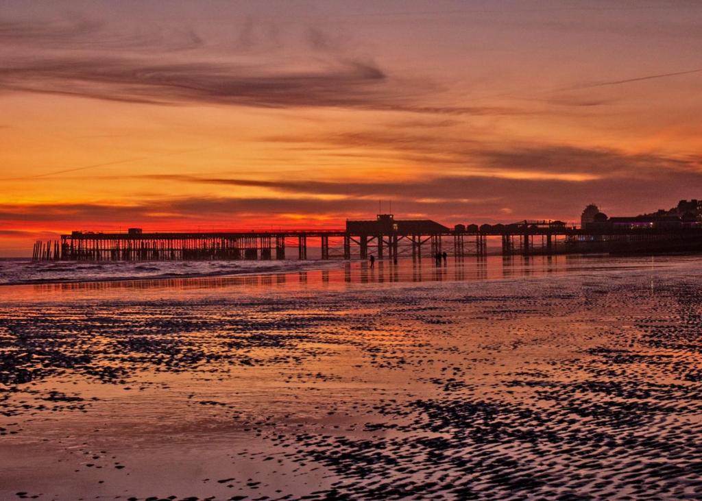 a pier on the beach at sunset at Church Retreat - A Magnificent Seaside Apartment-Award Winning in Hastings