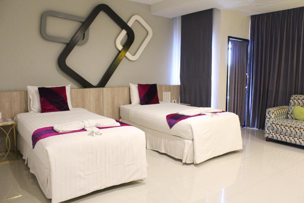 a hotel room with two beds and a chair at Phitsanulok United in Phitsanulok