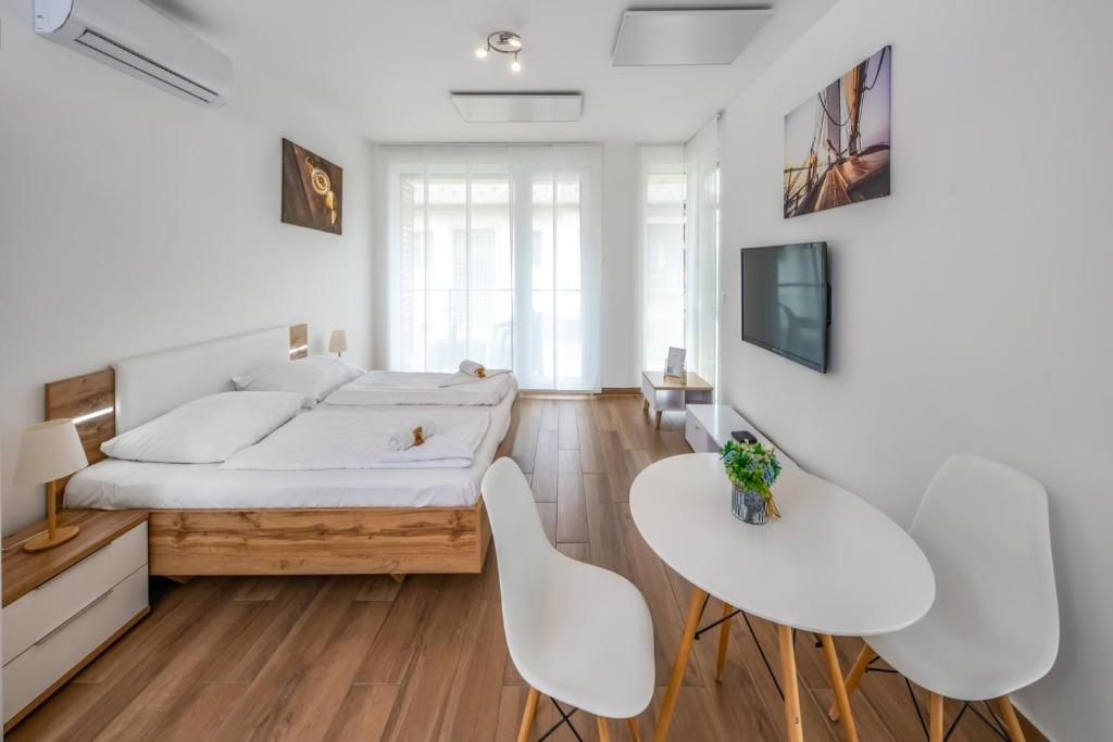 ein Schlafzimmer mit einem Bett und zwei weißen Stühlen in der Unterkunft Anchor Apartman by HelloBalatonlelle in Balatonlelle