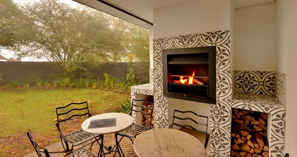 a fireplace with a fire in it with a table and chairs at Hilton Homestead by ANEW in Pietermaritzburg