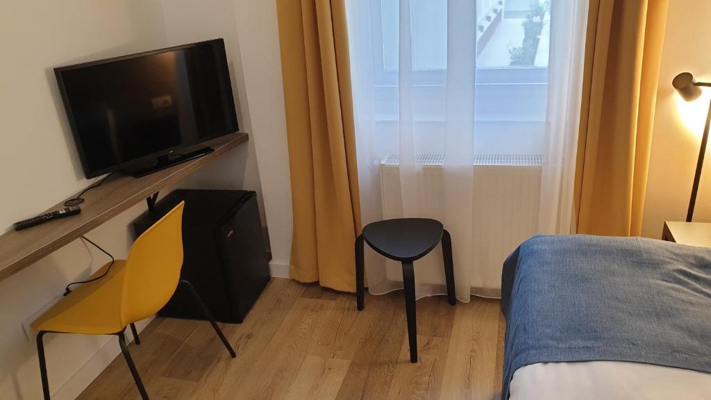 a bedroom with a bed and a tv and a chair at RES City Residence Hotel Budapest in Budapest