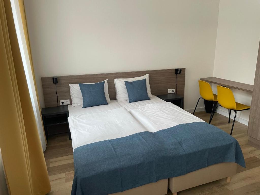 a bedroom with a bed and a desk with a yellow chair at RES City Residence Hotel Budapest in Budapest