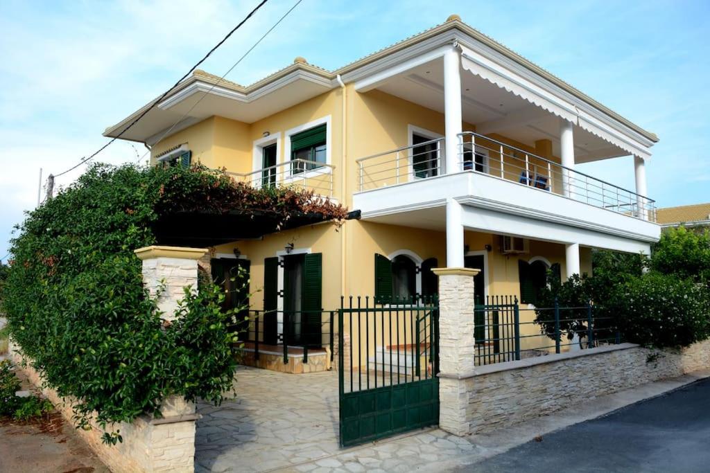 a yellow house with a fence in front of it at Panos Apartment in Mitikas