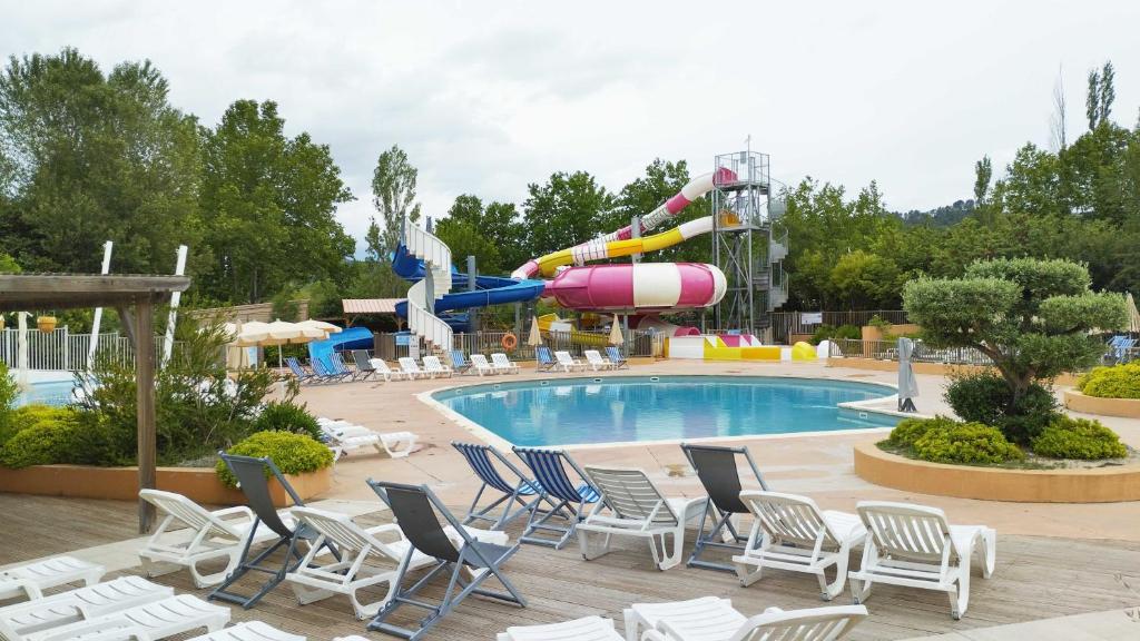 a pool with chairs and a water park at Mobil Home vue sur le lac dans un camping 4 étoiles à Cadenet in Cadenet