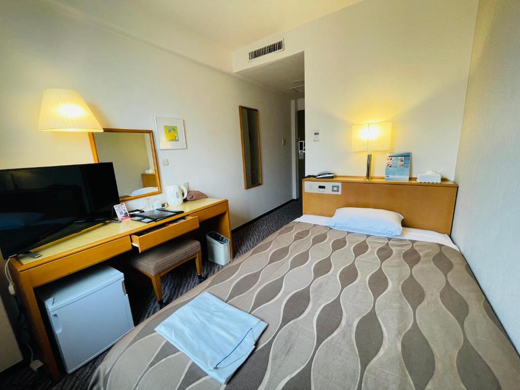 成田市にあるセンターホテル成田1のベッドとデスクが備わるホテルルームです。