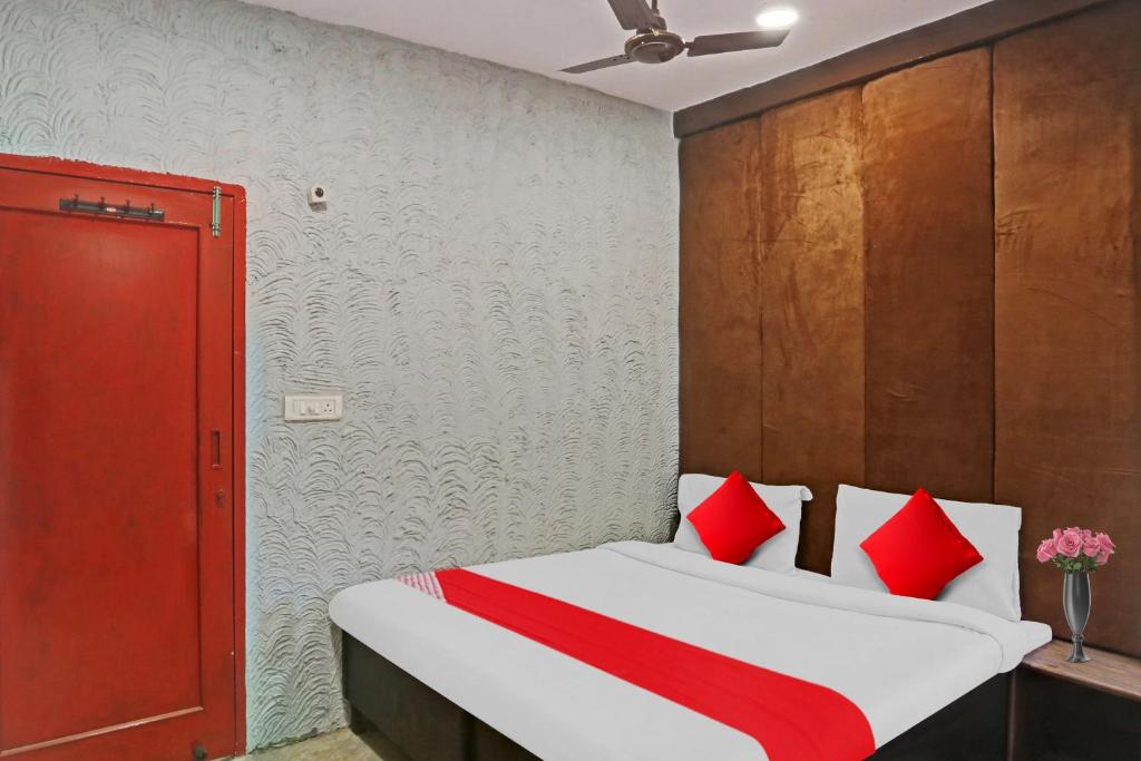 Flagship Kashish Residency في نيودلهي: غرفة نوم بسرير ومخدات حمراء وبيضاء