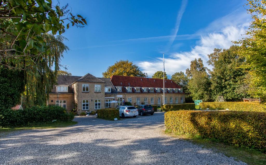 a large building with cars parked in the driveway at Fredensborg Vandrerhjem, i Kongens baghave in Fredensborg