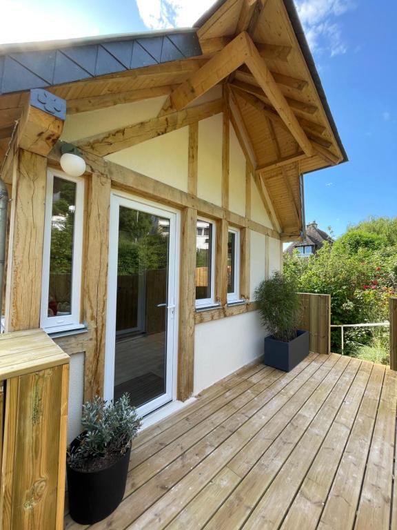 ein Haus mit einer Holzterrasse mit Markise in der Unterkunft La cabine de Deauville in Deauville