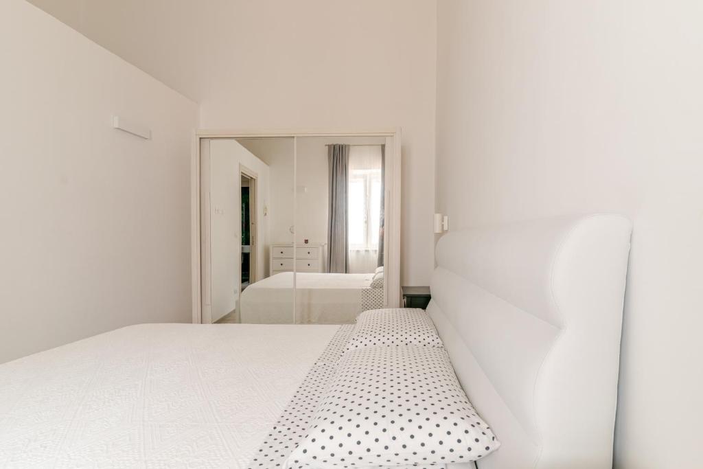 biała sypialnia z łóżkiem i lustrem w obiekcie La Casa di Nonna w mieście Ostuni