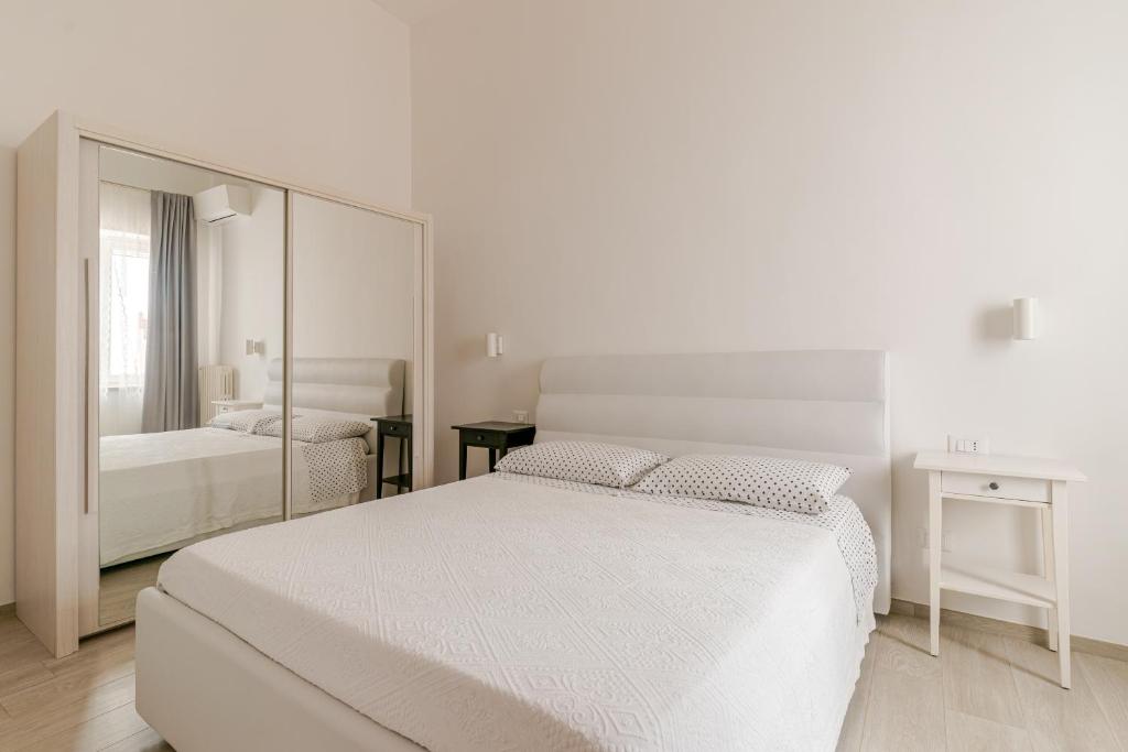 biała sypialnia z łóżkiem i lustrem w obiekcie La Casa di Nonna w mieście Ostuni