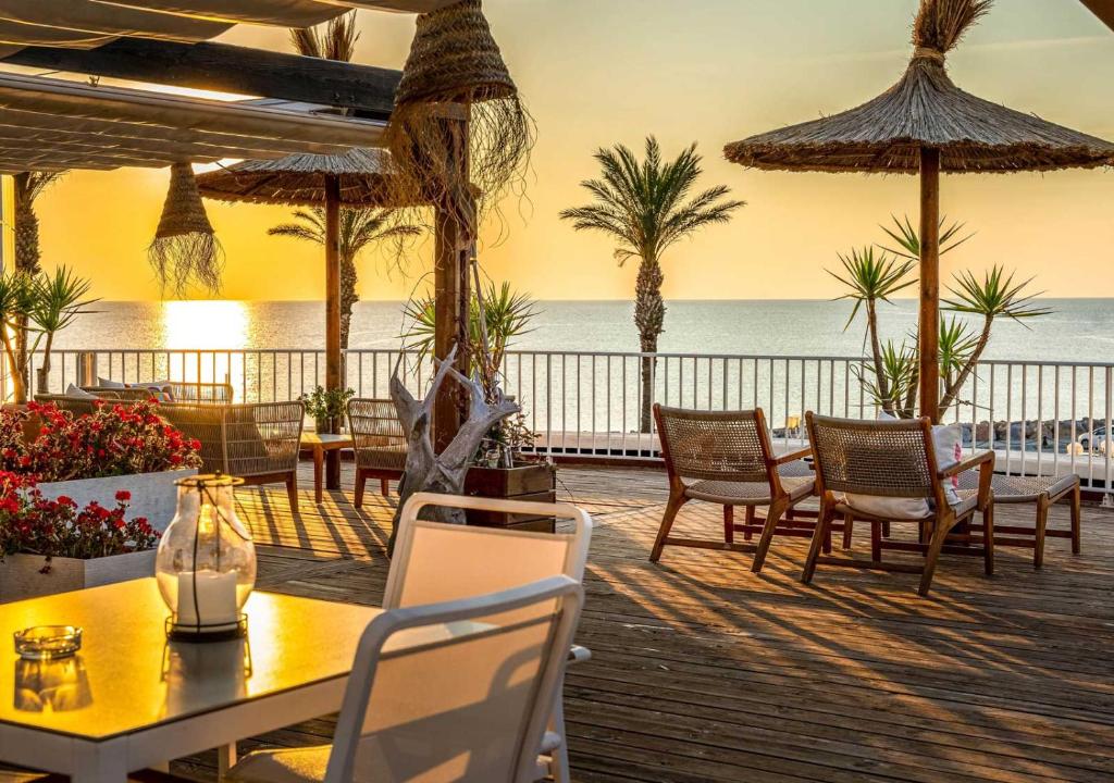 a patio with tables and chairs and the ocean at Bleu Mer Duplex & Suites in Saint-Cyprien