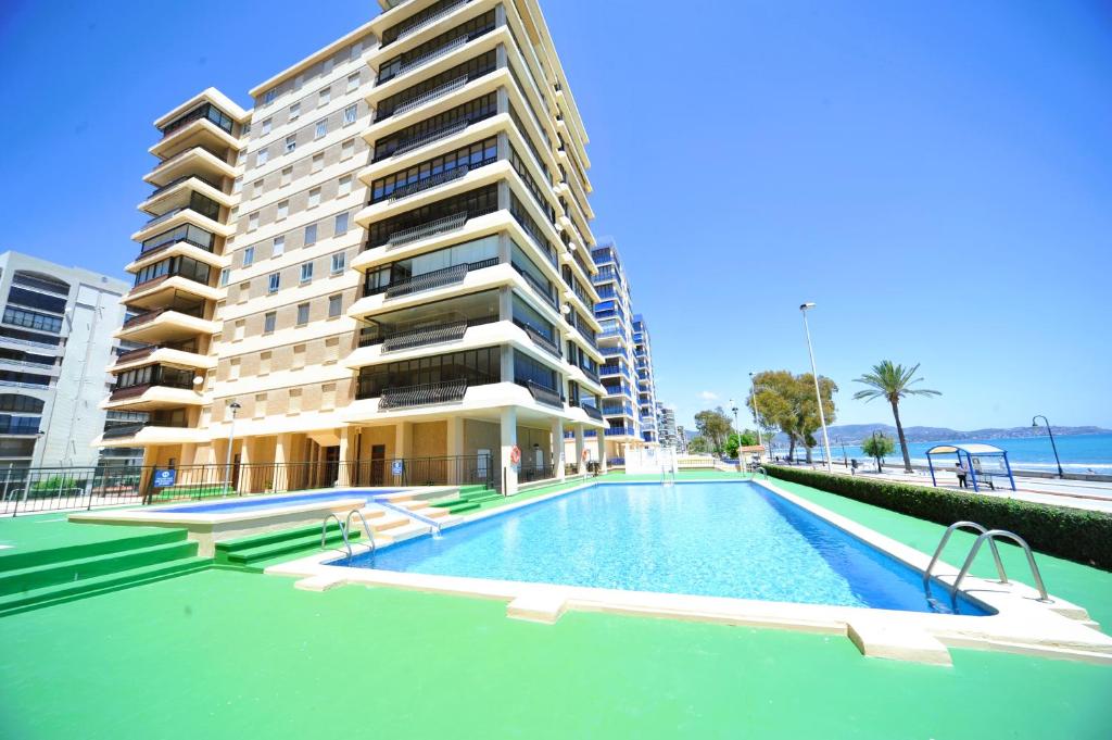 a swimming pool in front of a tall building at Castellmar vista mar Orangecosta in Benicàssim
