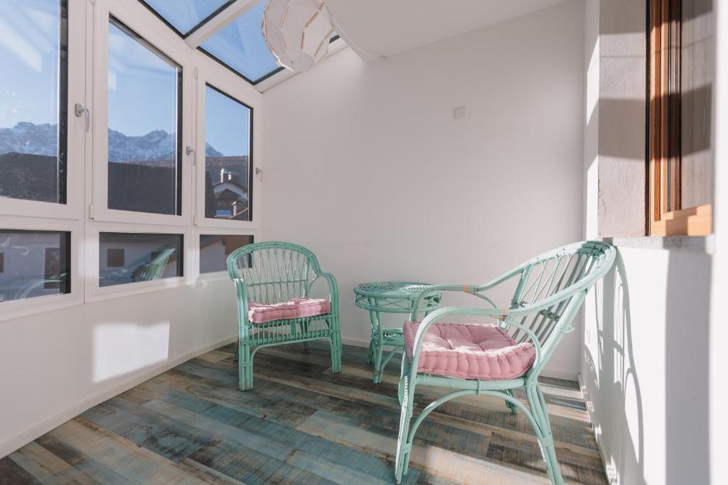 balcón con 2 sillas, mesa y ventanas en Alpenvilla Winklwiese, en Valdaora