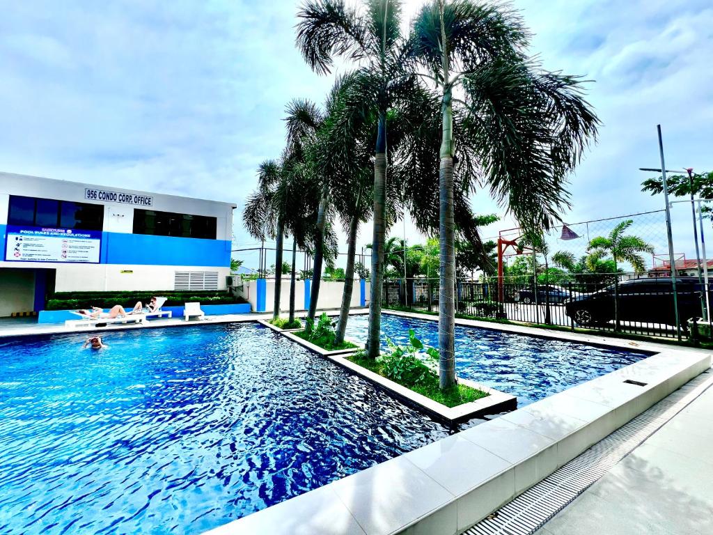 a swimming pool with palm trees in front of a building at Saekyung Condotel Near Airport in Lo-oc