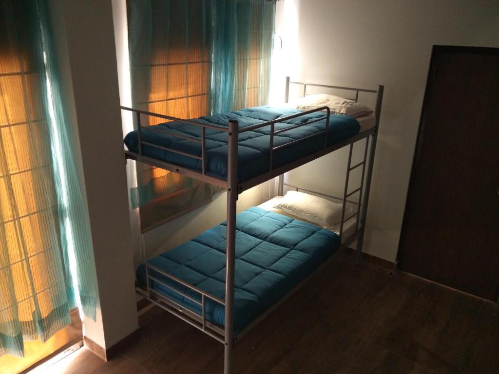 two bunk beds in a room with blue sheets at Joey's Hostel Delhi - 20 mins from Railway Station in New Delhi