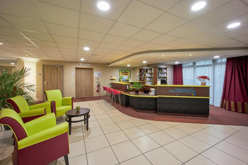 un hall d'hôpital avec des chaises vertes et une salle d'attente dans l'établissement Residence Seniors Les Essentielles, à Caen