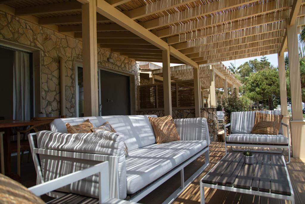 a porch with a couch and chairs on a patio at Elya Beach Luxury Suites in Ayios Theodhoros
