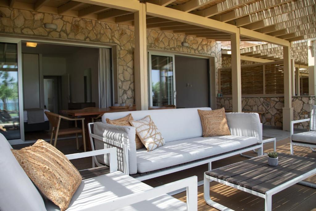 a patio with a couch and chairs and a table at Elya Beach Luxury Suites in Ayios Theodhoros