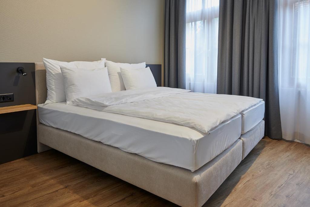 JeussHotel Jäger Jeuss - Murten - Self-Check-in的卧室里有一张大床，床单和枕头都是白色的