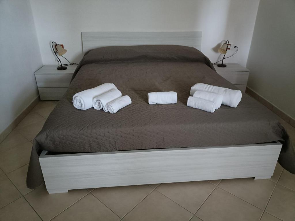 a bed with three rolls of towels on it at Gelsi Holiday Home La Maddalena in La Maddalena
