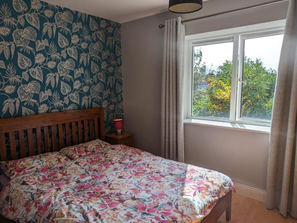 - une chambre avec un lit doté d'un couvre-lit floral et d'une fenêtre dans l'établissement Latin Quarter Cosy Apartment, à Galway